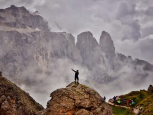 A hiker on a rock infront of the Sella mountain range
